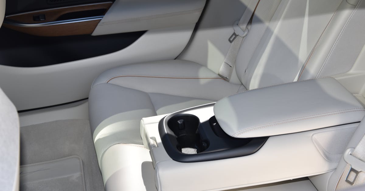 Elegant white leather car interior showcasing luxury and comfort with armrest and cup holder.