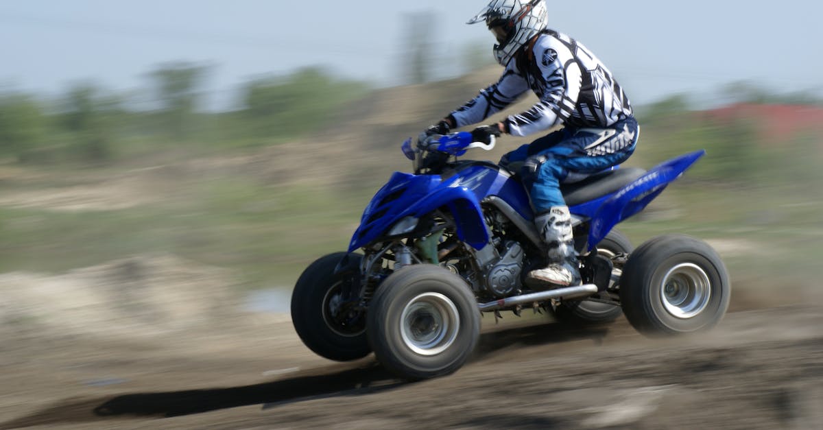 Action-packed image of a rider on a blue ATV speeding across a dirt track.