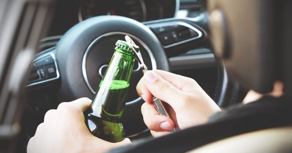 Hands opening a beer bottle inside a car, highlighting the importance of safe driving and awareness of road dangers.